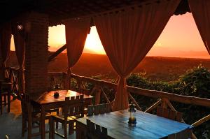 - deux tables sur une terrasse couverte avec vue sur le coucher du soleil dans l'établissement Pousada Villa Real, à Areia