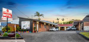 Port Macquarie Motel في ميناء ماكواري: فندق فيه سيارات متوقفة في موقف للسيارات