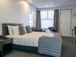 a hotel room with a large bed and chairs at Durham Court Motor Inn in Tauranga