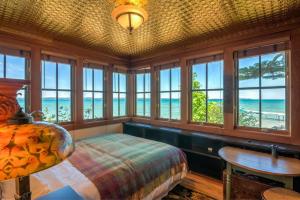 a bedroom with a bed and a table and windows at The Spring Lighthouse B&B in Elk Rapids