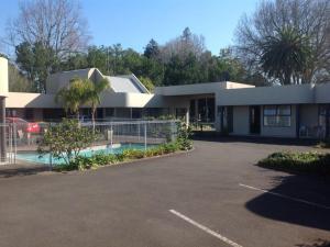 a house with a car parked in front of a parking lot at Durham Court Motor Inn in Tauranga