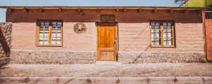 un edificio con una porta in legno e due finestre di Diablito Atacama Hostel a San Pedro de Atacama