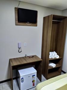 a hotel room with a desk and a tv on the wall at Hotel Campina Executivo in Campina Grande