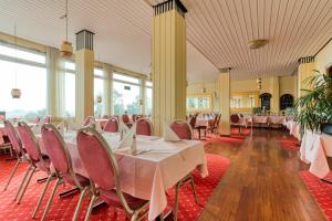 a banquet hall with tables and chairs and windows at FF&E Hotel Dania in Puttgarden