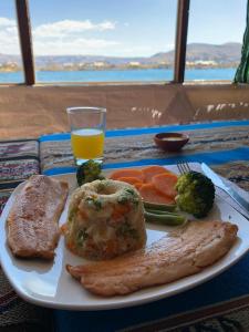 a plate of food with meat and vegetables and a glass of orange juice at Uros Titicaca Khantaniwa Lodge in Puno