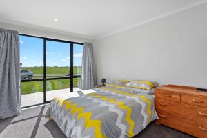 a bedroom with a bed and a large window at Kukumoa At the Beach in Opotiki