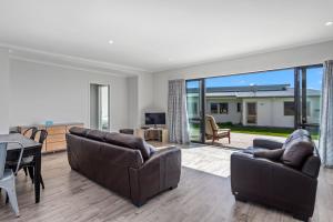 a living room with two couches and a table at Kukumoa At the Beach in Opotiki