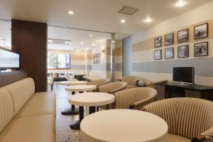 um restaurante com mesas e cadeiras e uma televisão em Keio Presso Inn Kanda em Tóquio