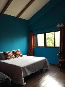 1 dormitorio con 1 cama con paredes y ventanas azules en 麵包樹舍 Breadfruit B&B, en Guangfu