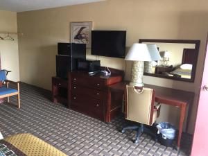 Habitación de hotel con escritorio, cama y TV. en Budget Inn Motel, en Storm Lake