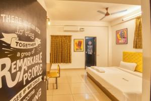 Zimmer mit einem Bett und einer Wand mit einem Schild in der Unterkunft La Maison Charu in Puducherry