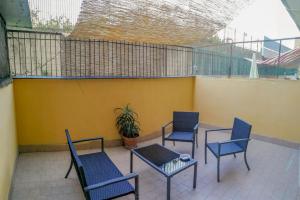 a patio with four chairs and a table and a yellow wall at Metro Guest House in Naples