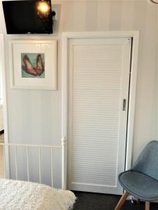 a bedroom with a door with a chair and a television at 66 Chaucer B&B with Complimentary Breakfast to Go Bag in Cambridge