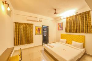 a bedroom with a bed with a yellow headboard at La Maison Charu in Puducherry
