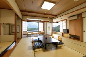 een woonkamer met een tafel, stoelen en ramen bij Hotel Shion in Morioka