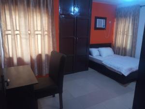 a small bedroom with a bed and a chair at Tiffany Apartments in Ibadan
