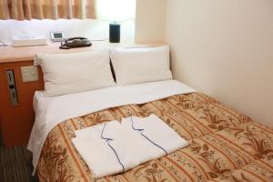 un letto in una stanza d'albergo con due cuscini di Hotel Ikeda a Nagasaki