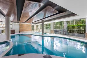 a large swimming pool with blue water in a building at Meriton Suites Waterloo in Sydney