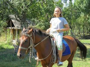 a young girl is riding on a horse at Pensiunea Adeluta in Călimăneşti