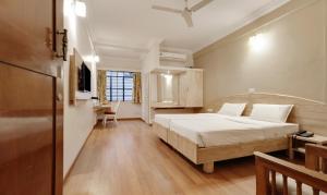 a hotel room with a bed and a desk and a bedroom at Hotel Vellara in Bangalore