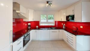 - une cuisine avec des placards blancs et des murs rouges dans l'établissement Mara MA3, à Blatten bei Naters