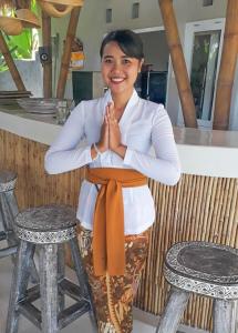 Uma mulher sentada num banco com as mãos à frente. em Coco Verde Bali Resort em Tanah Lot