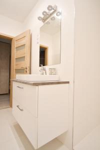 La salle de bains blanche est pourvue d'un lavabo et d'un miroir. dans l'établissement Moment Apartments, à Szolnok