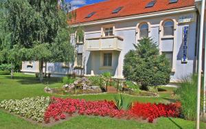 un bâtiment avec un jardin fleuri devant lui dans l'établissement Hotel Prezident, à Palić