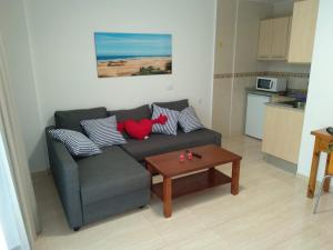 een woonkamer met een bank met kussens en een tafel bij Apartamentos Teror - Yumbo in Playa del Inglés
