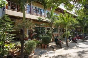 a building with palm trees and motorcycles parked in front of it at Silver Sands Resort - Koh Tao in Ko Tao