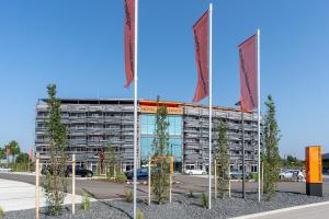 um edifício com bandeiras em frente a um parque de estacionamento em Augsburg Hotel Sonnenhof em Gersthofen