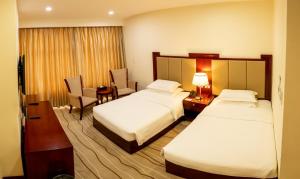 a hotel room with two beds and a desk at Swiss-Belhotel Blulane in Manila