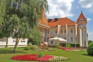 un grand bâtiment avec un jardin en face dans l'établissement Hotel Prezident, à Palić