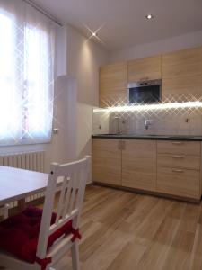 een keuken met houten kasten en een tafel en een stoel bij Giudei House Minisuite - self check-in in Bologna