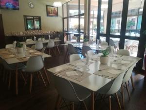 una sala da pranzo con tavoli, sedie e finestre bianche di Vhafamadi Bed And Breakfast a Sibasa