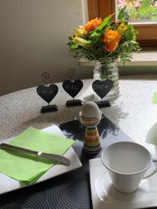 une table avec un vase de fleurs et un vase de fleurs orange dans l'établissement Gemütliche Ferienwohnung in ländlicher Idylle, à Vöhl