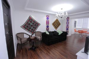 sala de estar con sofá negro y sillas en Overlooking Registan Square Luxury 2 Bedrooms Apartment, en Samarkand