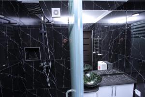a black tiled bathroom with a sink and a mirror at Overlooking Registan Square Luxury 2 Bedrooms Apartment in Samarkand