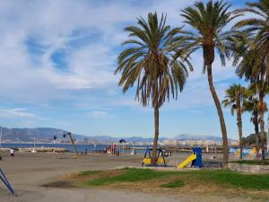 two palm trees and a playground on the beach at El Nogal Home in Málaga