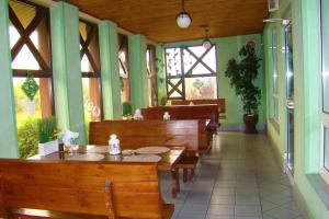 a restaurant with wooden tables and benches and windows at Zajazd Mistral in Nowa Wieś