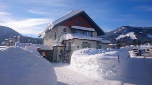 una casa ricoperta di neve di fronte a una montagna di Haus Hubertusheim a Schladming