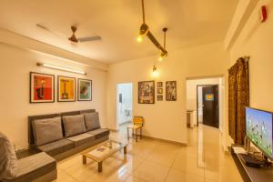 uma sala de estar com um sofá e uma televisão em La Maison Charu em Pondicherry