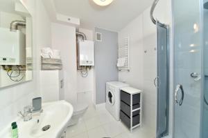 カルパチにあるApartament Szarotka - Apartamentujの白いバスルーム(シンク、洗濯機付)