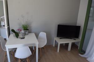 a living room with a white table and a television at Peter's Cottage, Near Fiscardo, Kefalonia in Fiskardo