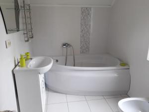 a white bathroom with a tub and a sink at Sweet Apartment in Truskavets