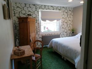 a bedroom with a bed and a table and a window at logement en campagne in Landemer