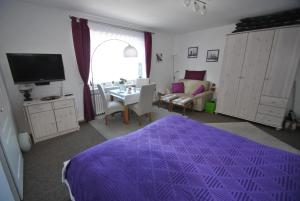 um quarto com uma cama roxa e uma sala de estar em Haus Rehblick FeWo-App-2 em Sankt Andreasberg