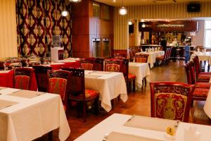 a dining room with tables and chairs with white tables and red seats at Platinum Hotel Ulaanbaatar in Ulaanbaatar
