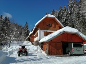 a snowmobile parked in front of a house in the snow at POHORJE HOUSE 2 FOUR APPARTMETNS in Oplotnica