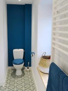 a bathroom with a toilet and a blue wall at L'atelier d'artiste charmant T2 centre historique in Dinan